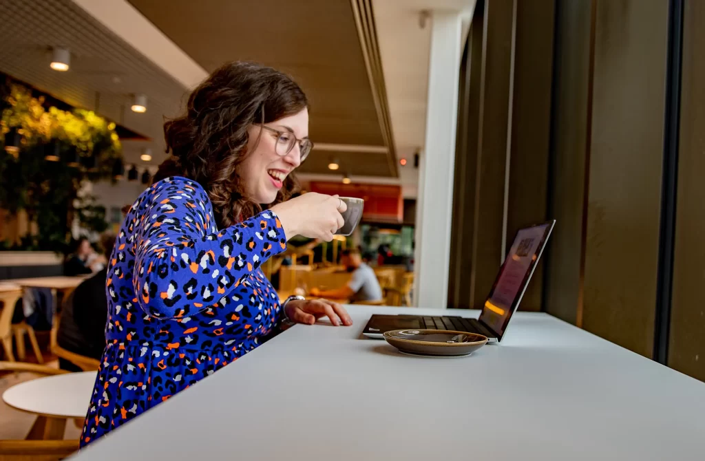 Sophie from Three Beams thinking drinking coffee in front of a laptop